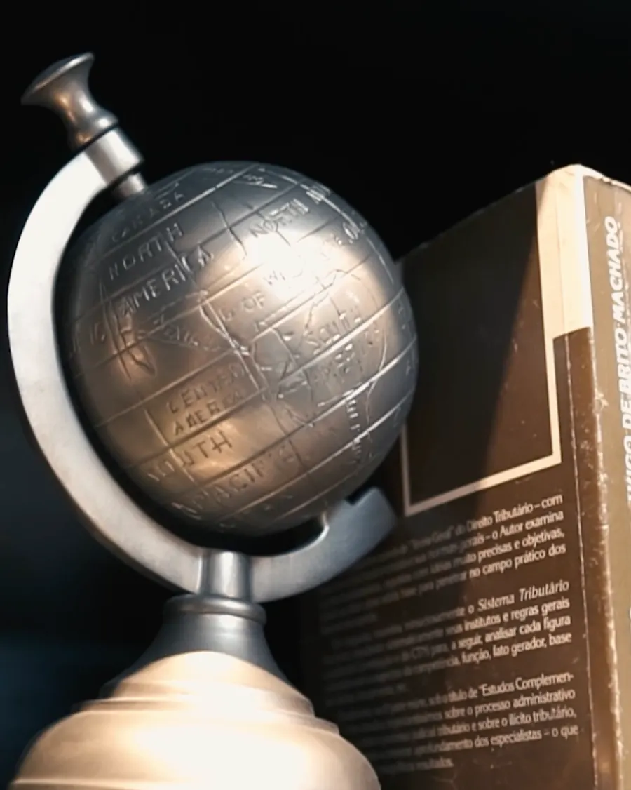 Livro de Direito Tributário e globo sobre a mesa do escritório